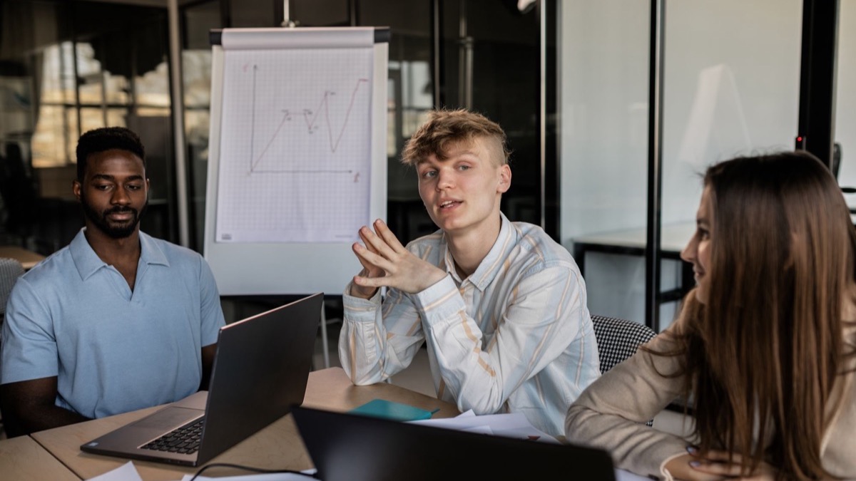 Three colleagues standing in a modern office discussing a business strategy
