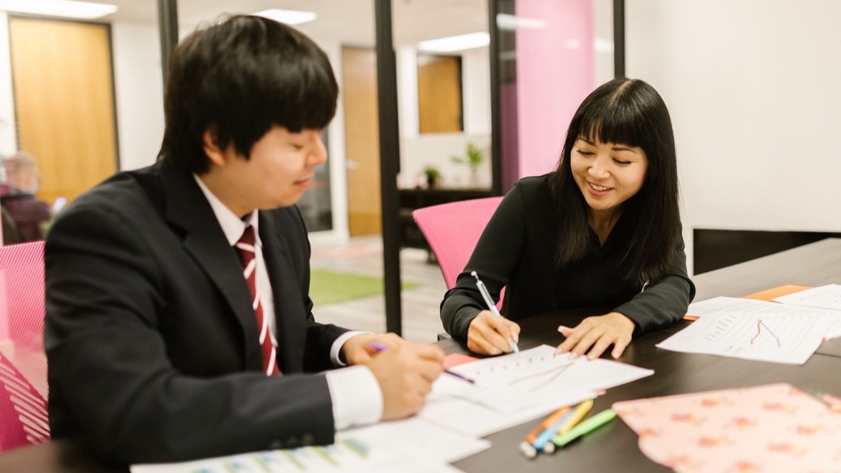 A team seated around a table in an office meeting, reviewing printed documents together