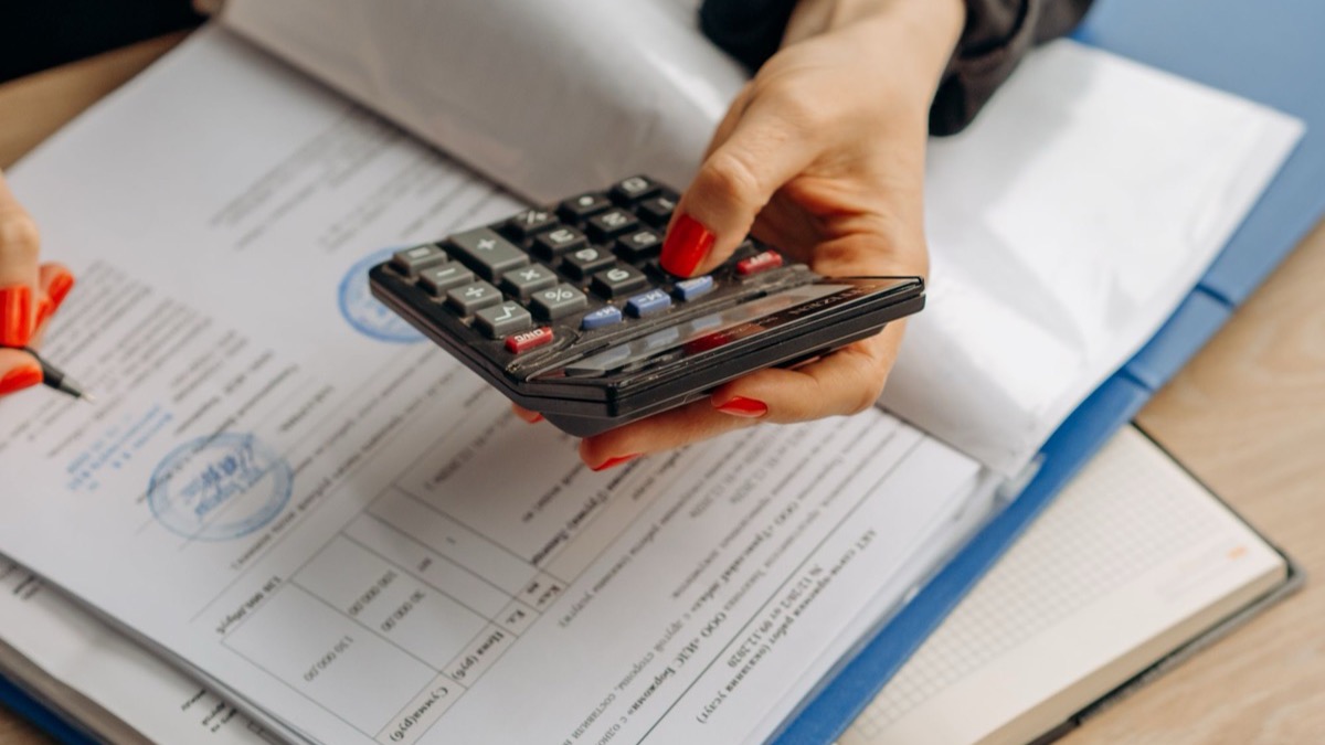 A person working through accounting documents with a calculator