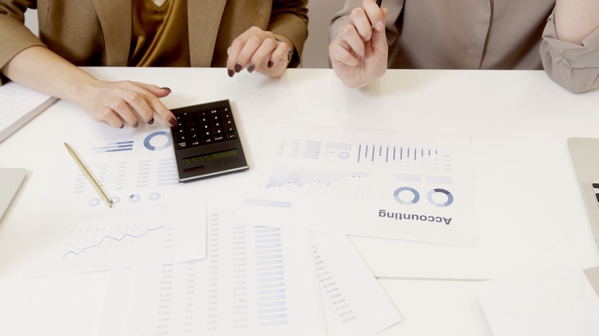 Two people reviewing financial documents with a calculator on the desk