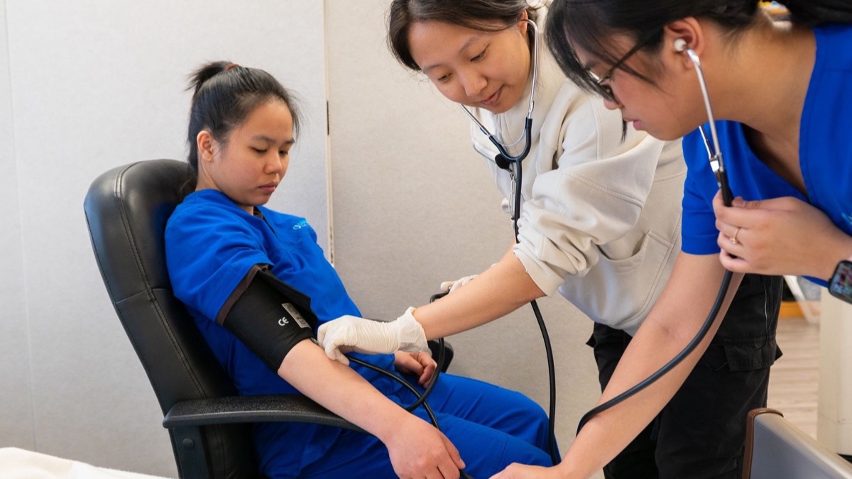 Healthcare trainees taking a blood pressure reading in a clinical room