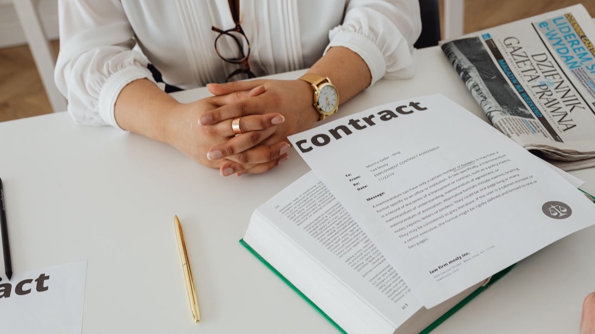 A person reading a contract at a desk with legal papers and a notebook