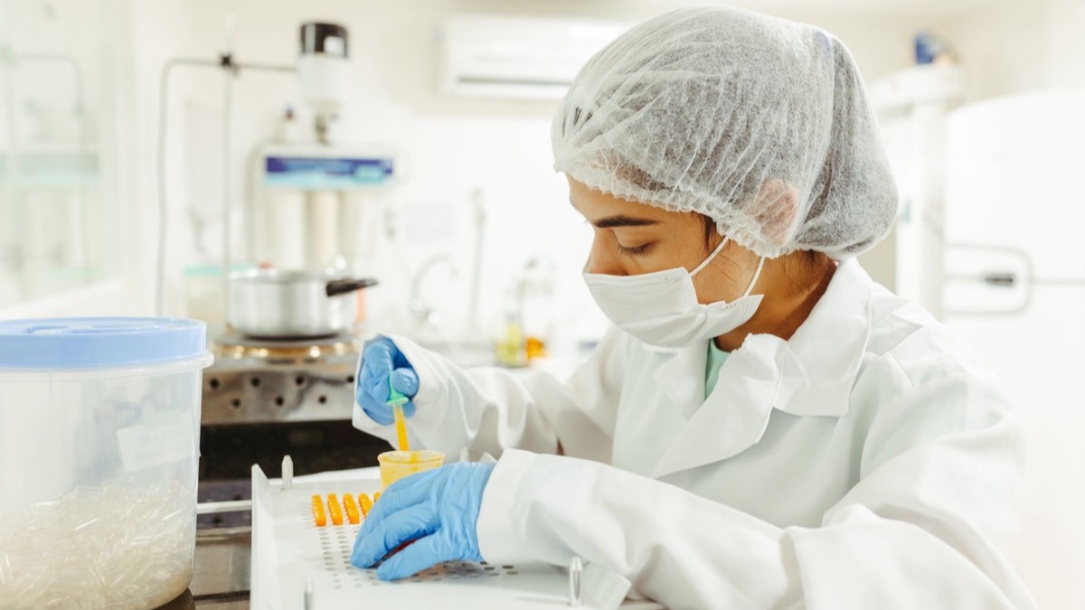 A researcher in protective equipment carrying out a careful laboratory procedure