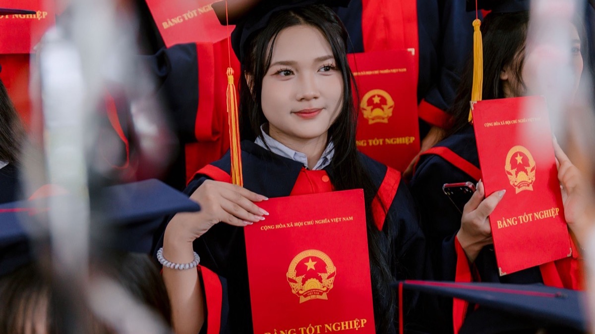 Các tân cử nhân đội mũ mặc áo tốt nghiệp cầm bằng sau buổi lễ